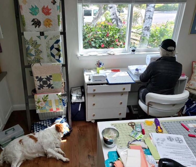 Julie celebrates National Quilting Day in 2021 in her sewing room with Cooper.