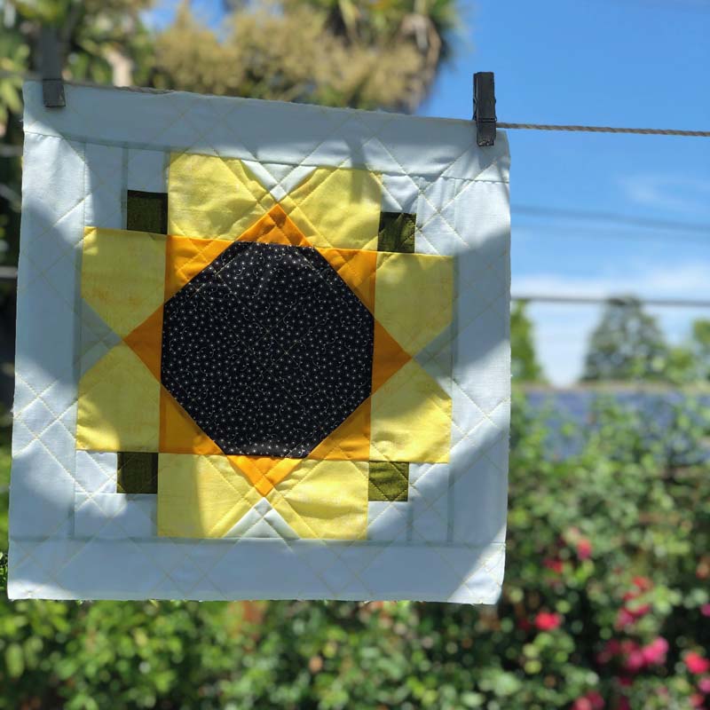 This Garden Sunflower Quilt Block is quilted and hanging in the sunshine.  Free pattern download is available at The Crafty Quilter