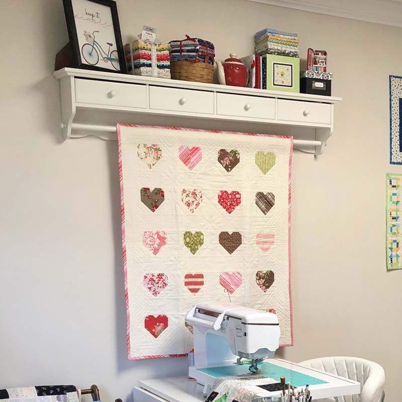 Shelf unit found at a consignment shop is perfect for hanging quilts and storing thread.