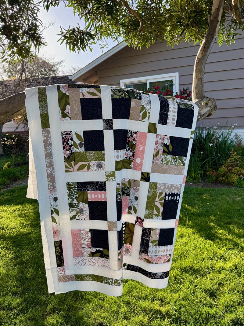 Jelly Roll Cabin quilt draped over a tree branch.